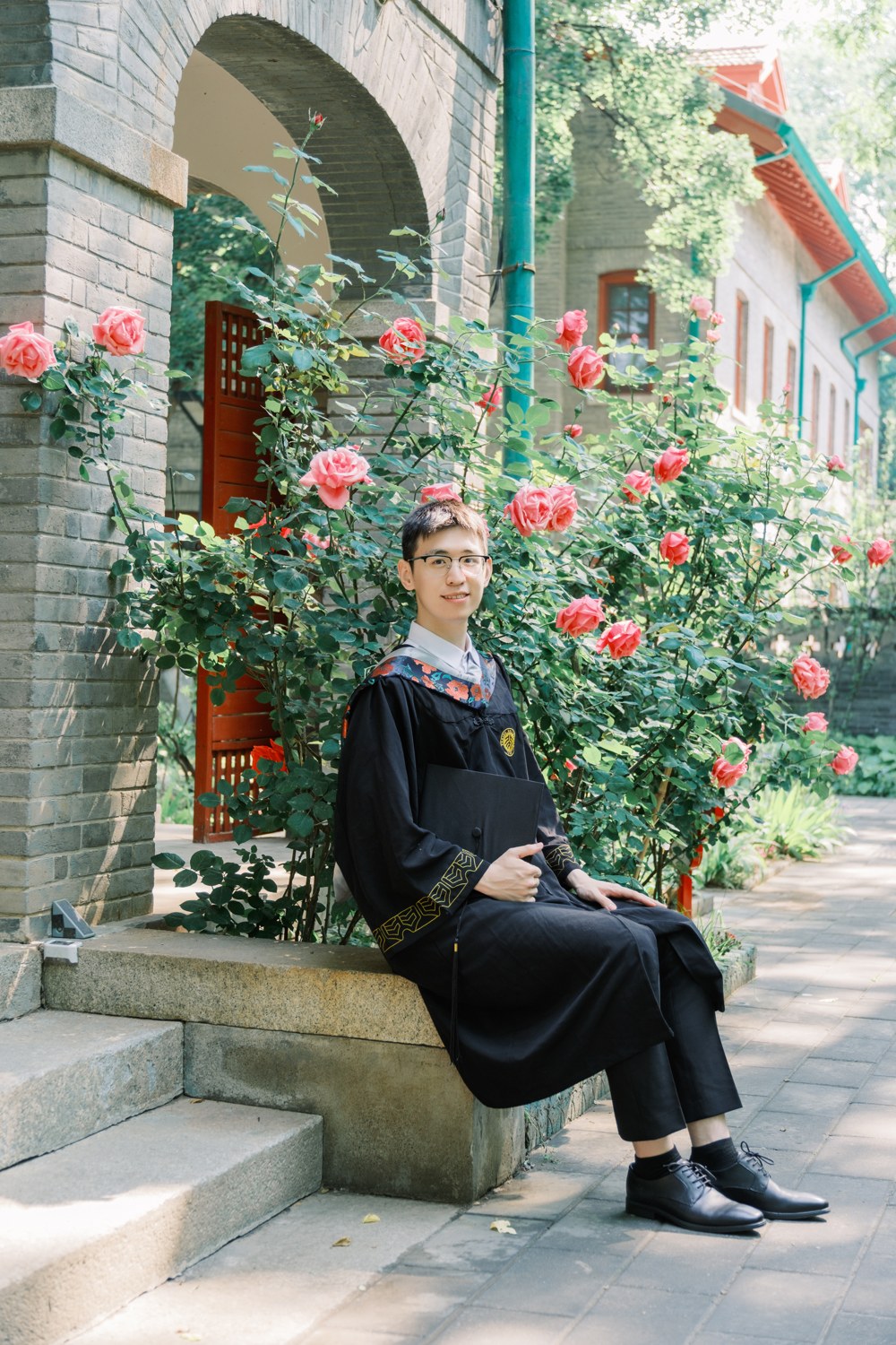 Tianyi Xu in graduation robes beside roses at Peking University